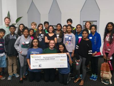 students pose with large check award